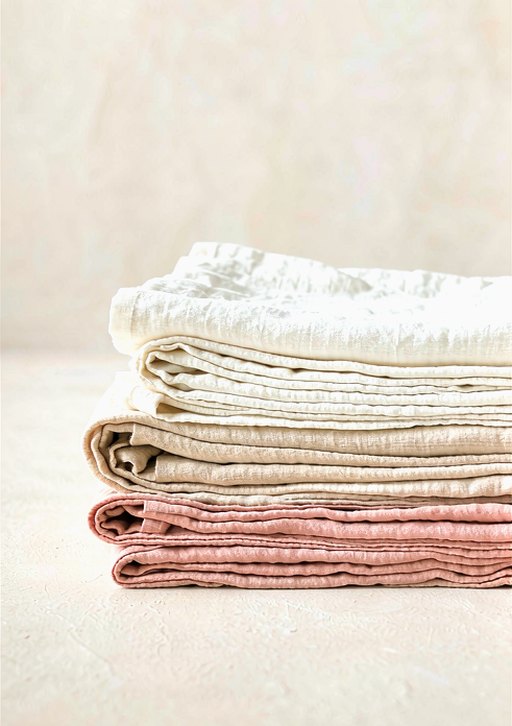 A stack of folded linen textiles in warm neutrals